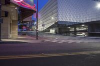 an empty city street with some tall buildings in the background and lights at the side