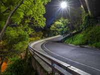 the road is winding in to a tunnel that runs around a hill with lush green trees around it