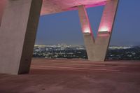 the pink light shines on the street below a tall concrete structure in the city