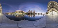 two spherical views of city buildings and a pond at night, in a panoramic picture