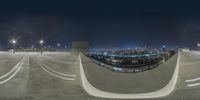 a fisheye lens lensing a picture of a large parking lot at night with city skyline in the background