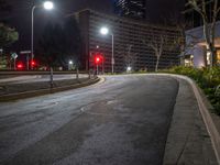 an empty street with two red lights at the corner of it and many tall buildings