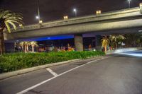 two people are on motorbikes with helmets at night under an overpass with lights on