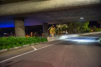 two people are on motorbikes with helmets at night under an overpass with lights on