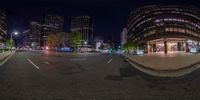 a view of a street with tall buildings and a clock at night from the side