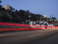 an expressway with motion bluring red light on the road next to a white building