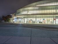 the outside of an arena building at night with a fire hydrant on the sidewalk