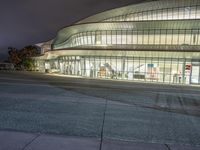 the outside of an arena building at night with a fire hydrant on the sidewalk