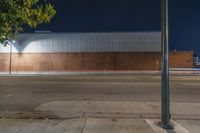 a traffic light on an empty sidewalk in front of a building at night, with the lights turned on