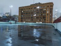 a wet roof at night next to tall buildings and skyscrapers with reflections in the puddle
