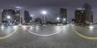 street with cars and skyscrapers at night near cityscape in nighttime time taken with fish eye lens