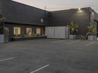 the empty parking lot is decorated with palm trees and other plants on the side of the building