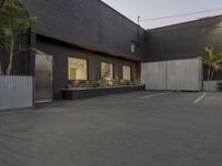 the empty parking lot is decorated with palm trees and other plants on the side of the building