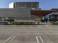 a building that is next to a parking lot with an open space on the sidewalk