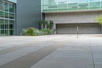 a person on a skateboard is in the street near building and trees while another person walks away