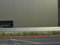 an empty parking lot and a fence behind it with some building glass in the background