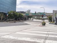 a city street at the intersection of the street and underpass above it is two pedestrian walk signs