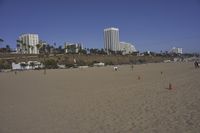 a group of people on a beach next to the ocean and a resort on the horizon
