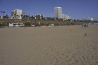 a group of people on a beach next to the ocean and a resort on the horizon