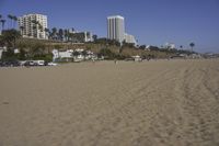 a group of people on a beach next to the ocean and a resort on the horizon