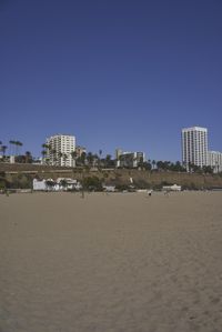 a group of people on a beach next to the ocean and a resort on the horizon