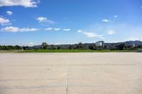 a large concrete lot with a clear sky in the background and a tree line in the middle