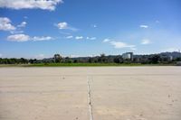 a large concrete lot with a clear sky in the background and a tree line in the middle