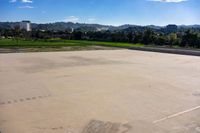 the empty parking lot is surrounded by lush greenery and a mountain view as a plane flies overhead