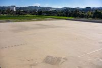 the empty parking lot is surrounded by lush greenery and a mountain view as a plane flies overhead