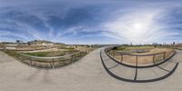 a fish eye view of a park with some people and a fence under the sky