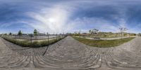 this is a very fisheye photo of an outdoor park area with a fenced in area and trees in the distance