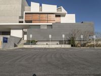 an empty parking lot outside a building with white walls and a parking area sign on the side