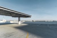 a view of an air port from a car parking lot under a large canopy to a plane