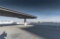 a view of an air port from a car parking lot under a large canopy to a plane