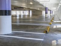 a parking garage with two yellow curb barriers on one side and one in the middle