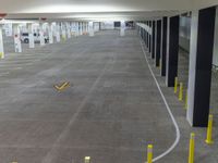 an empty parking garage with poles and a sign on the floor next to it and parked cars