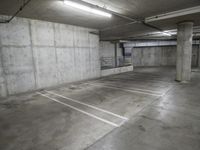 empty concrete parking garage with white lines painted in various directions and light at the end