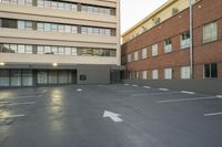 the empty parking lot is next to the large building which the apartments are located behind