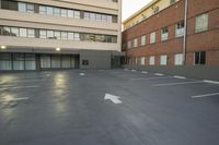 the empty parking lot is next to the large building which the apartments are located behind