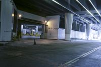 a building in a parking garage at night time with light coming through the windows and a black umbrella sitting on the pavement