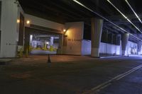 a building in a parking garage at night time with light coming through the windows and a black umbrella sitting on the pavement