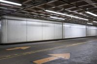 an empty concrete parking garage with no doors and a yellow arrow painted on the floor