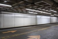 an empty concrete parking garage with no doors and a yellow arrow painted on the floor