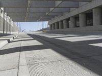 an open parking garage with concrete floors and long shadows on the floor and ceiling concrete structures in the area with large windows