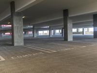 a parking garage with concrete pillars and floors that have no sign marking on the cement