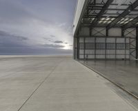 an empty parking garage sits on concrete and metal flooring with a cloudy sky in the background