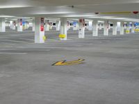 a parking garage with a sign on the floor near an arrow painted in concrete, and three parking spots are in the floor