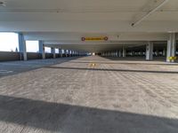 an empty parking garage with two yellow yellow warning signs attached to the ceiling and no people in it