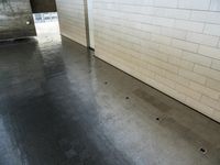 a small tiled wall in the center of an empty parking garage with a floor drain