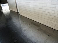 a small tiled wall in the center of an empty parking garage with a floor drain